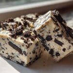 Two rich squares of white chocolate Oreo fudge studded with dark cookie pieces, sitting on a white plate.