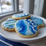 Close-up of sugar cookies decorated with vibrant blue and white marbled royal icing using a cookie icing recipe.