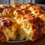 Close-up of cheesy hawaiian roll garlic bread, showing melted cheese stretching between the rolls.