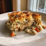 A generous serving of creamy chicken wild rice casserole with shredded chicken, carrots, and a golden, crunchy topping.
