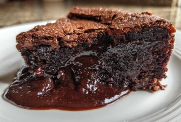 Close-up of a moist slice of chocolate pudding cake oozing rich, dark chocolate sauce onto a white plate.