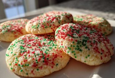 A close-up shot of soft, round christmas sprinkle sugar cookies topped with red and green sprinkles.