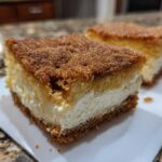 Two slices of rich churro cheesecake with a thick cinnamon-sugar topping served on a white plate.