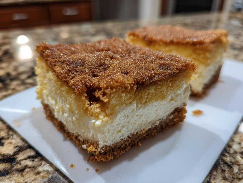 Two slices of rich churro cheesecake with a thick cinnamon-sugar topping served on a white plate.