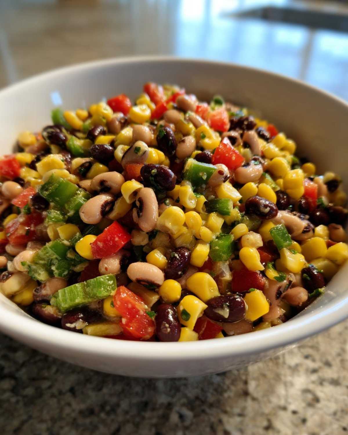Close-up of vibrant cowboy caviar featuring black beans, corn, tomatoes, and peppers in a white bowl.