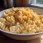 A close-up of creamy cheesy chicken pasta made with rotini noodles, topped with melted cheddar cheese.
