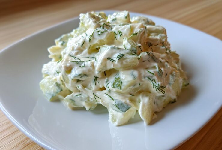 A mound of creamy cucumber salad mixed with dill, resembling a thick pickle dip texture.