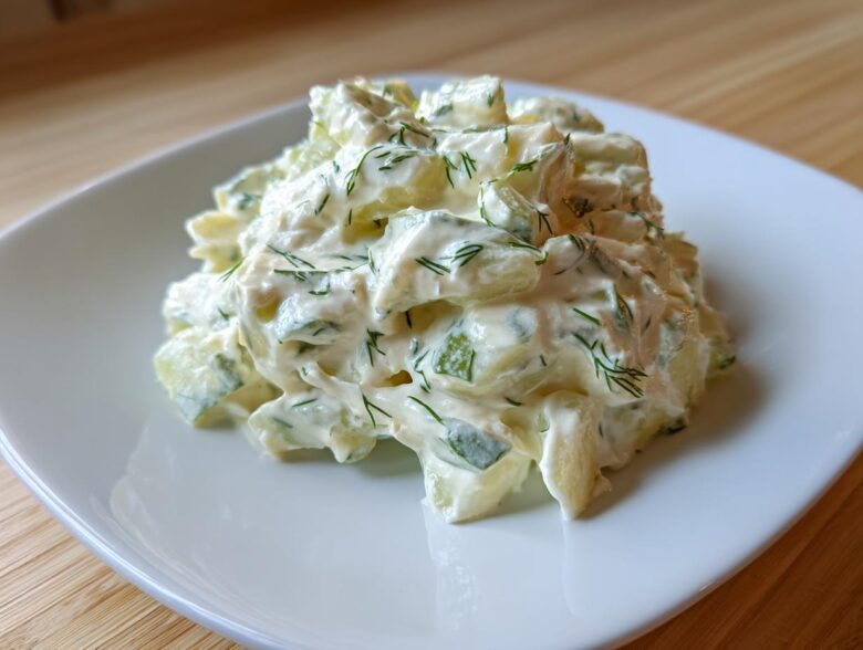 A mound of creamy cucumber salad mixed with dill, resembling a thick pickle dip texture.