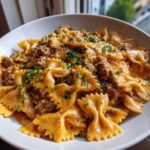Close-up of creamy parmesan garlic beef bowtie pasta topped with fresh parsley in a white bowl.