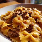 Close-up of creamy parmesan garlic beef bowtie pasta coated in a rich, savory sauce.