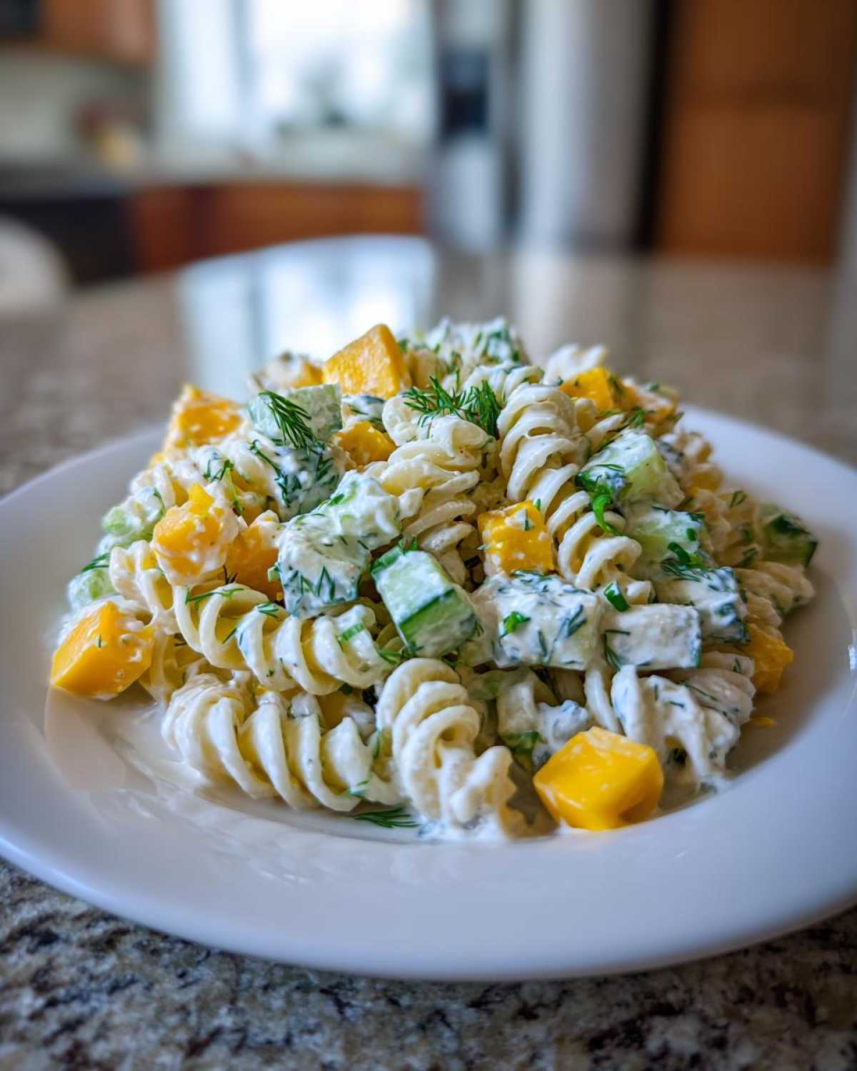 Close-up of creamy pickle pasta salad featuring rotini pasta, diced pickles, yellow bell pepper or cheese, and fresh dill.