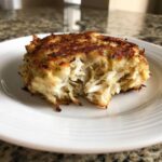 A golden-brown, pan-seared maryland crab cake broken open to show large chunks of white crab meat inside.