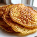 Close-up of a stack of fluffy discard pancakes showing lacy, hole-filled texture and golden-brown edges.