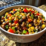 A vibrant bowl of homemade cowboy caviar featuring black-eyed peas, corn, black beans, and diced peppers.