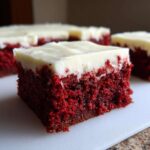 Close-up of a fudgy red velvet brownies square topped with thick cream cheese frosting.