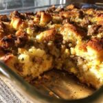 Close-up of baked sausage stuffing with a golden crust and visible chunks of bread and sausage.