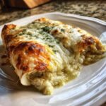 Close-up of cheesy green chile chicken enchiladas smothered in melted cheese and green sauce.