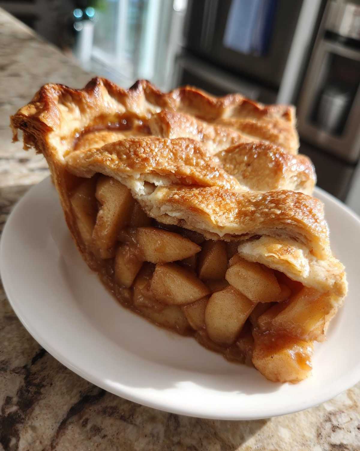 A generous slice of homemade apple pie showing thick, spiced apple filling and a golden, flaky crust.