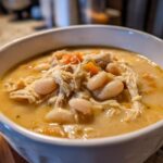 Close-up of a white bowl filled with creamy instant pot white chicken chili, featuring shredded chicken and white beans.
