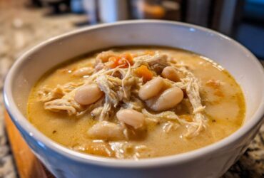 Close-up of a white bowl filled with creamy instant pot white chicken chili, featuring shredded chicken and white beans.