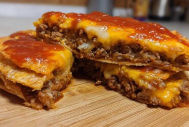 Cross-section view of a homemade Mexican pizza showing layers of seasoned ground beef, melted cheese, and red sauce.