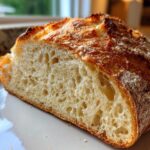 Close-up of a thick slice of homemade no-knead bread showing a beautiful open crumb structure and crust.