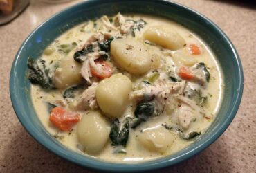 Close-up of a bowl of creamy olive garden chicken gnocchi soup, featuring plump gnocchi, shredded chicken, spinach, and carrots.