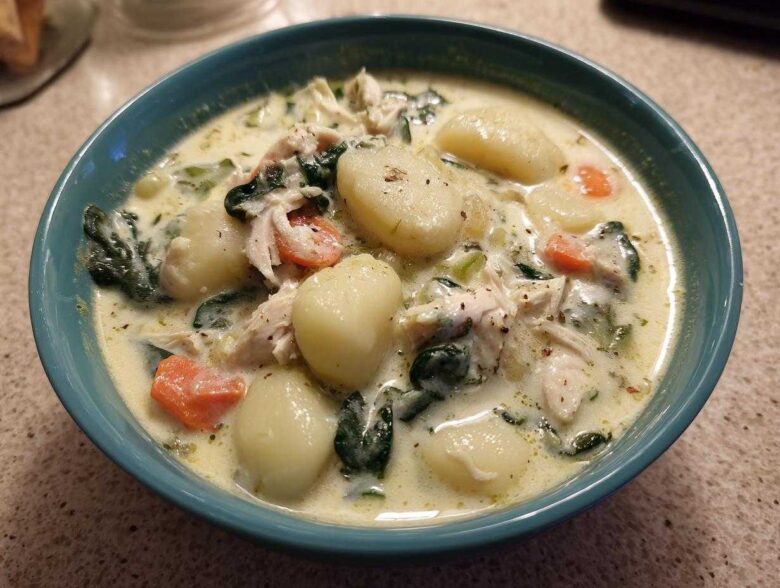 Close-up of a bowl of creamy olive garden chicken gnocchi soup, featuring plump gnocchi, shredded chicken, spinach, and carrots.