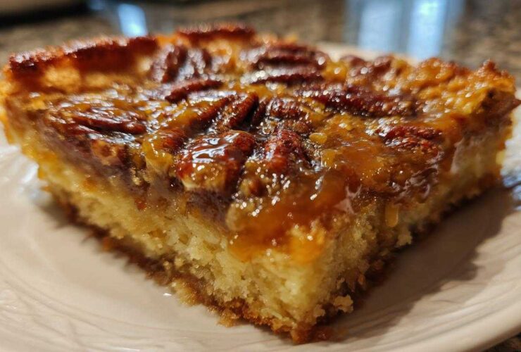 Close-up of a moist slice of pecan pie cobbler recipe with a sticky, caramelized pecan topping.