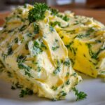Close-up of two portions of rich, yellow garlic butter mixed with vibrant green parsley.