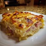 A thick, cheesy slice of baked scalloped potatoes and ham with a golden-brown crust.