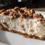 A close-up slice of silky pecan cream pie showing the thick, creamy filling and graham cracker crust topped with toasted pecans.