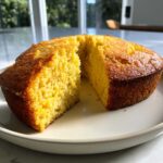 A golden, moist skillet cornbread with a slice cut out, showing the crumb texture.