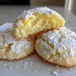 Close-up of soft, crinkle-topped lemon cookies dusted heavily with powdered sugar.