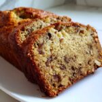 Close-up of two thick slices of moist sugar free banana bread featuring visible walnuts and a golden-brown crust.