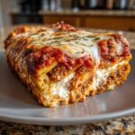 A thick, cheesy slice of baked pasta layered with meat sauce and ricotta cheese, ready to eat in this amazing pasta bake.