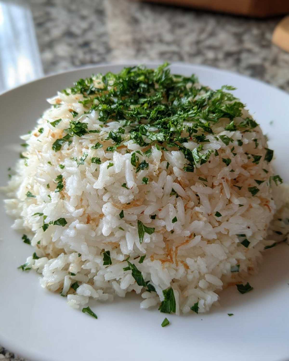 A mound of fluffy white rice pilaf seasoned with toasted vermicelli and topped generously with fresh chopped parsley.