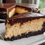 A close-up slice of rich peanut butter pie featuring a dark crust, creamy filling, and thick chocolate topping.
