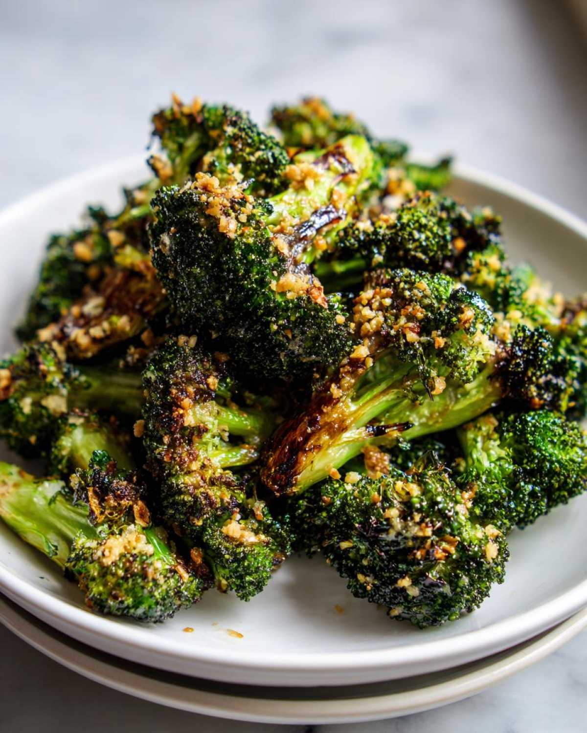 Close-up of perfectly charred and crispy roasted broccoli florets topped with golden breadcrumbs.