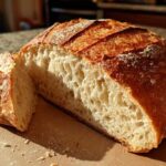 Cross-section of a rustic french bread loaf showing an open, airy crumb and golden crust.