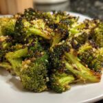 Close-up of perfectly cooked roasted broccoli florets, slightly charred and topped with garlic seasoning.