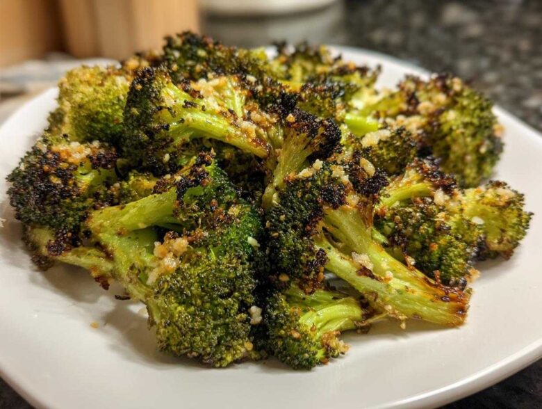 Close-up of perfectly cooked roasted broccoli florets, slightly charred and topped with garlic seasoning.