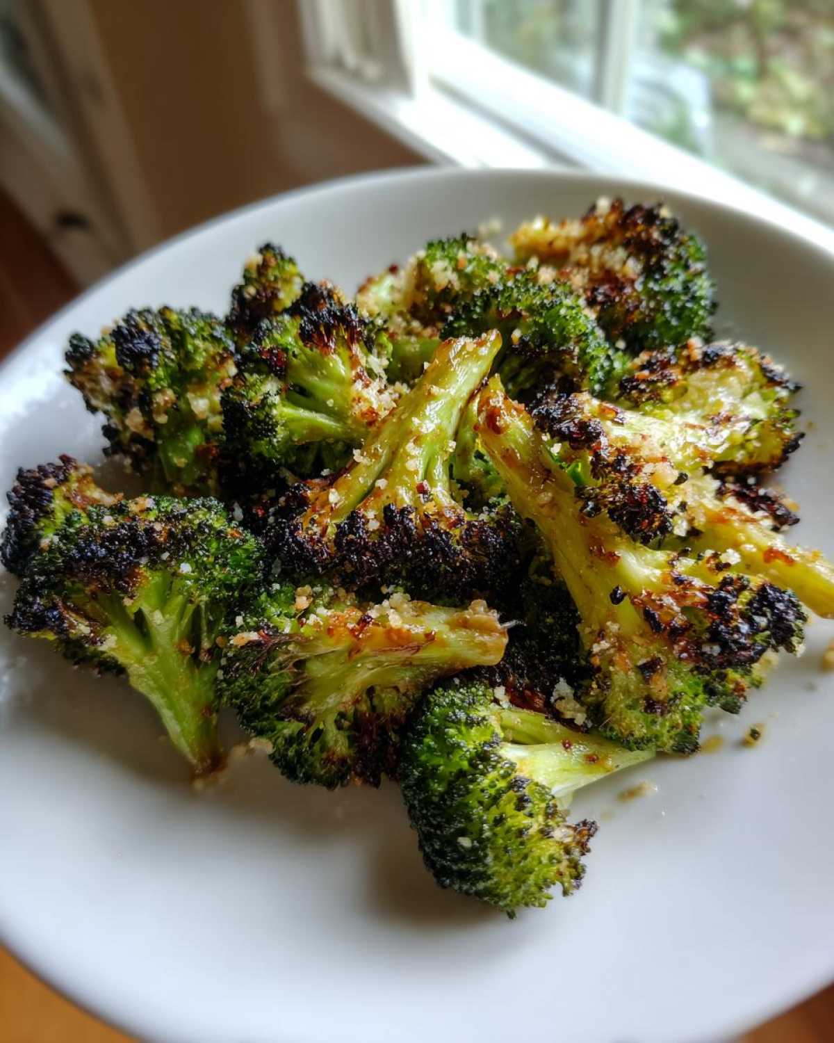 Close-up of perfectly roasted broccoli florets, slightly charred and sprinkled with grated cheese.