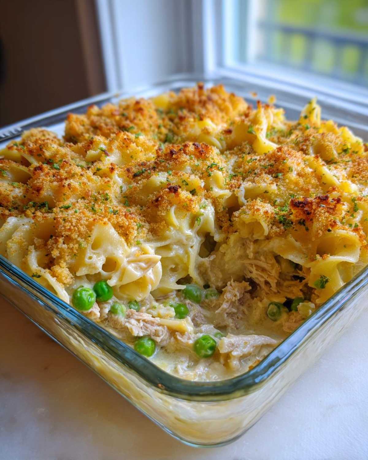 Close-up of creamy Tuna Casserole with egg noodles, peas, and a golden breadcrumb topping.