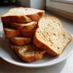 Stack of freshly sliced whole wheat bread showing a light crumb texture on a white plate.