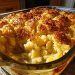 Close-up of a golden brown, bubbly apple cobbler recipe baked in a clear glass dish.