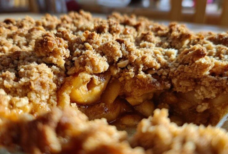 A close-up view showing the gooey, spiced apples beneath a thick, golden-brown, crunchy topping of an apple crisp recipe.