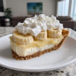A perfect slice of banana cream pie recipe with graham cracker crust, creamy filling, banana slices, and whipped cream.