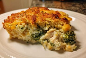 A close-up slice of creamy chicken broccoli rice casserole with a golden, crunchy topping.