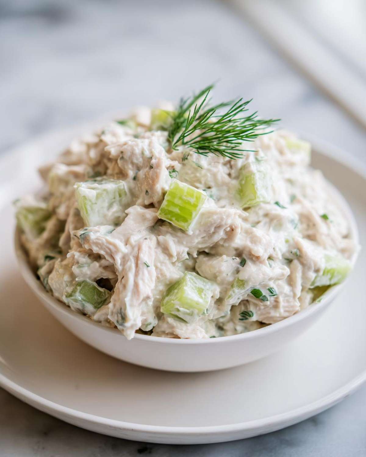 A close-up of creamy cottage cheese chicken salad mixed with celery chunks and topped with fresh dill.